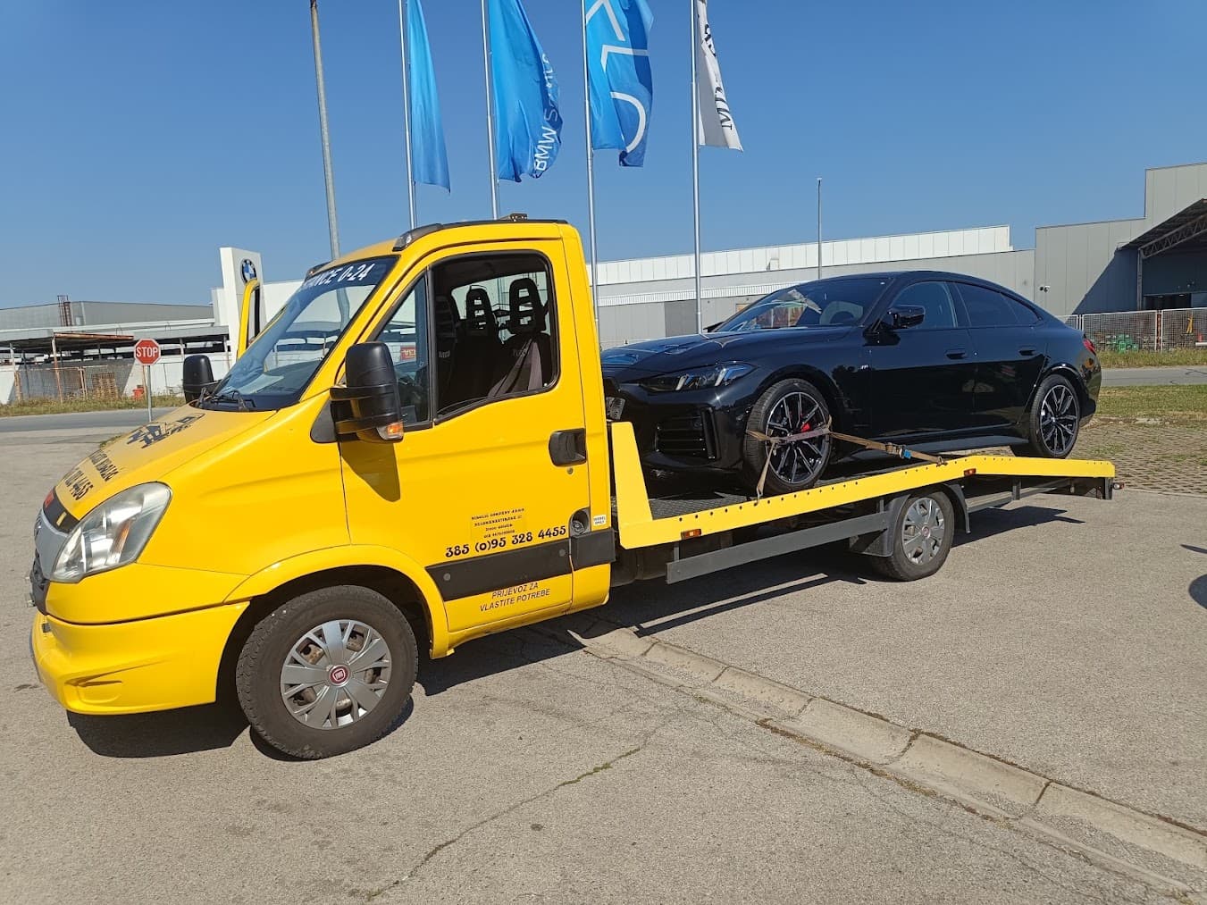 Vučno vozilo utovaruje osobni automobil ispred BMW salona